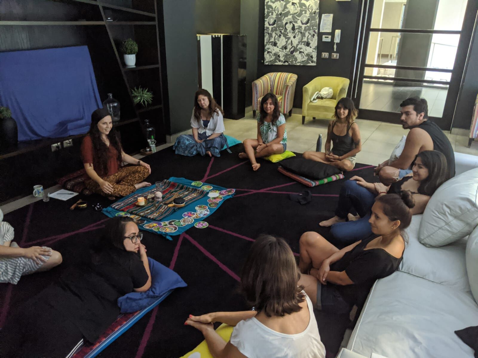 A group seated in a circle on the floor around a cacao ceremony altar
